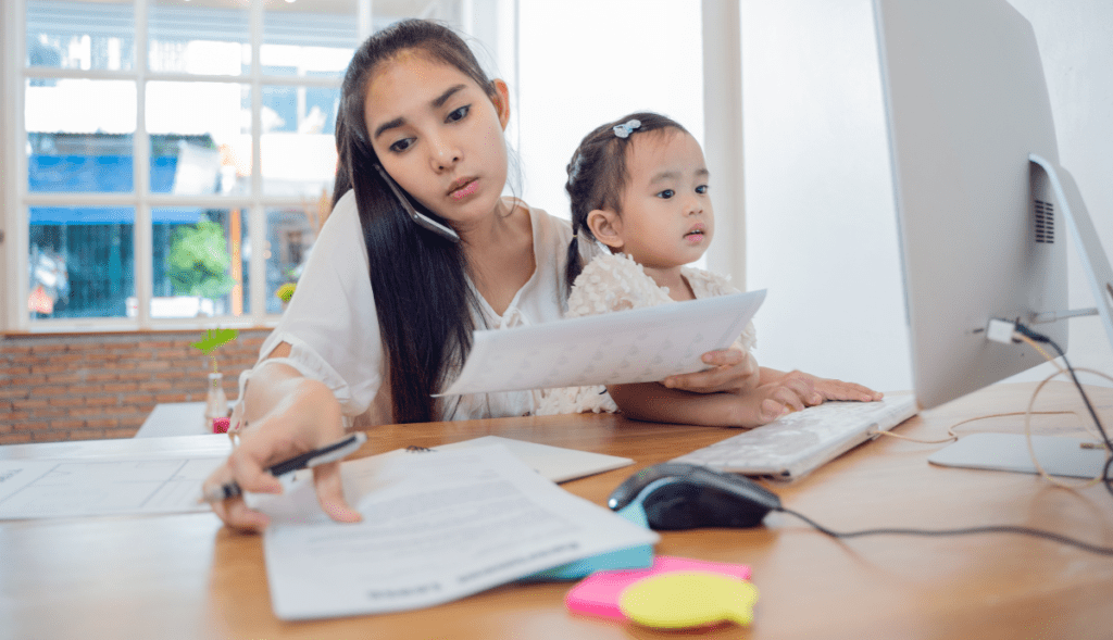 Working mother balancing work and childcare while holding her child